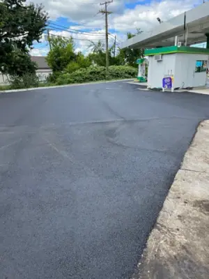 Asphalt forecourt alongside the canopy and station building.