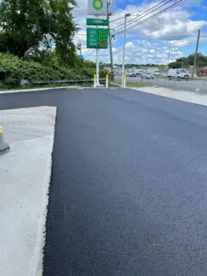 Asphalt apron beside the station entrance and roadside sign.