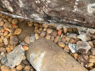 Pipe passing beneath the edge of the existing pavement.