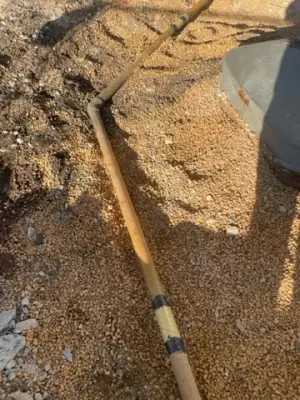 Exposed underground pipe and coupling in the excavated trench.