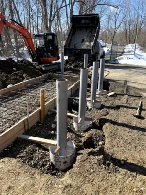 Vertical pipe risers and underground connections beside the prepared foundation.