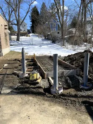 Vertical pipe risers and underground connections beside the prepared foundation.