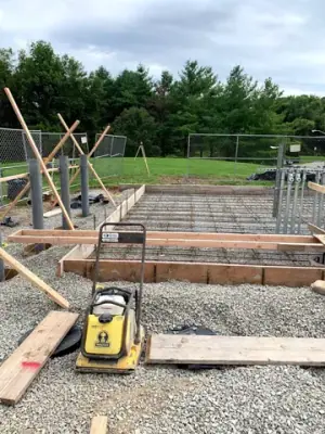 Timber forms, pipe risers, and aggregate base before concrete placement.