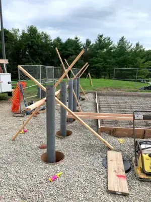 Timber forms, pipe risers, and aggregate base before concrete placement.