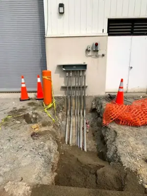 Conduit bank rising to electrical equipment on the facility wall.