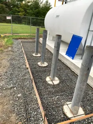Protective posts and reinforced concrete forms alongside the installed tanks.