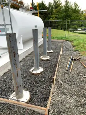 Protective posts and reinforced concrete forms alongside the installed tanks.