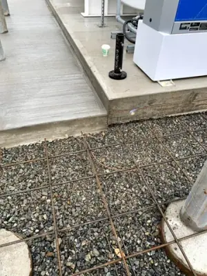 Concrete edge and aggregate beside the tank foundation.