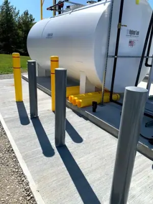 Aboveground tank protected by yellow bollards.