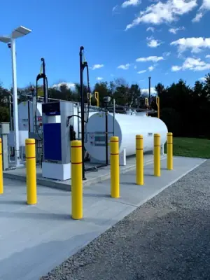 Installed fuel dispensers, aboveground tank, and yellow protective bollards.