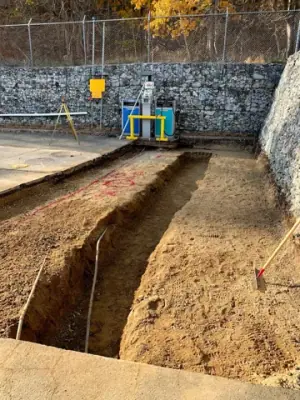 Excavated trench leading to the fueling equipment beside the retaining wall.