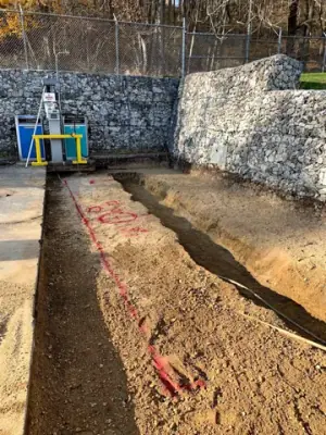 Excavated trench leading to the fueling equipment beside the retaining wall.