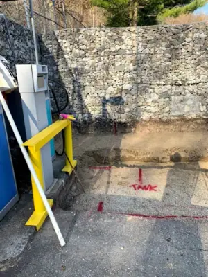Marked pavement beside the fueling equipment and retaining wall.