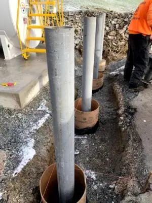 Protective steel posts set in excavated holes beside the concrete apron.