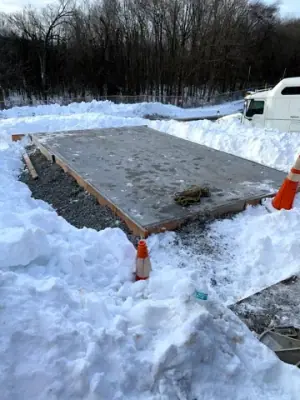 Snow around the excavated work area and existing concrete.