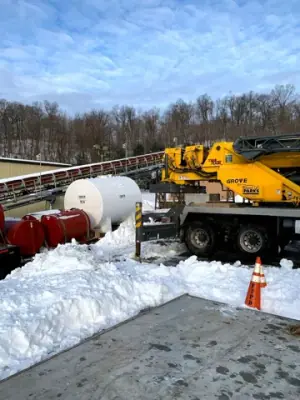 Crane truck and tank work at the snow-covered site.