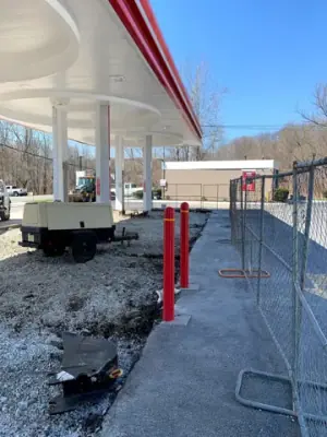 Removed forecourt pavement exposes aggregate around the fueling islands.