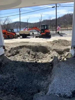 Excavated fueling-island area with open channels and earthmoving equipment.
