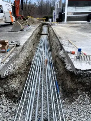 Parallel electrical conduits laid in an open trench beneath the forecourt.