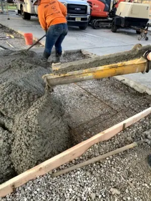 A worker places fresh concrete within the timber forms.