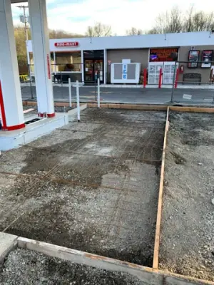 Prepared concrete bays with reinforcement and formwork around the fueling area.