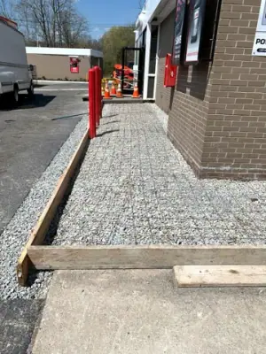 Formed gravel walkway beside the building and protective red posts.