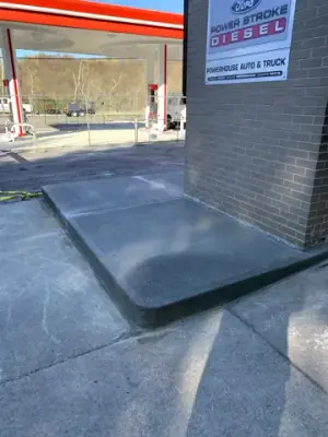 Concrete entrance landing at the storefront door.