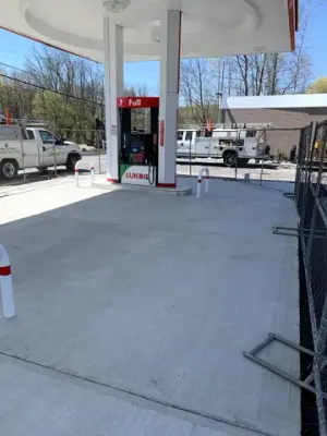 Concrete forecourt surface beside a dispenser island.