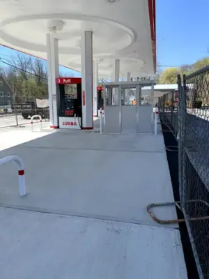 Finished fueling lanes, dispensers, and protective rails beneath the canopy.