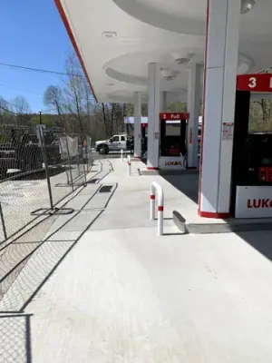 Finished fueling lanes, dispensers, and protective rails beneath the canopy.