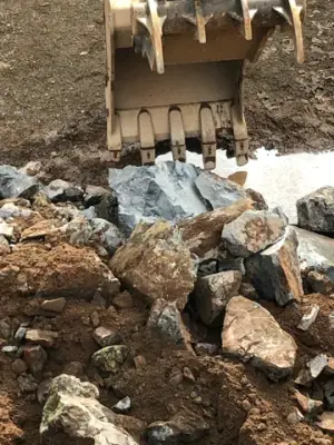 Excavator bucket above broken rock.