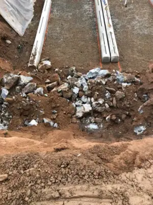 Excavation floor and equipment tracks beside exposed rock.