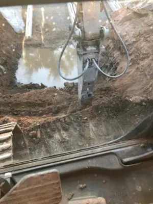Water and hoses in the excavated tank area.