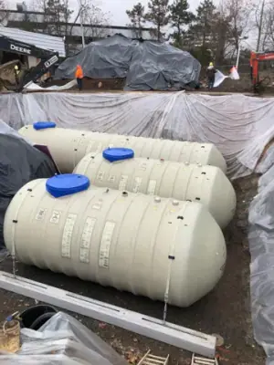 Multiple new underground tanks positioned side by side in the excavation.