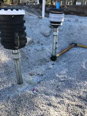 Tank risers and containment fittings projecting above aggregate bedding.