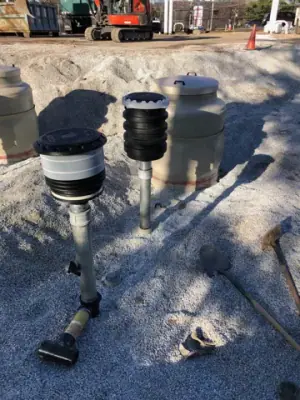Group of tank risers and containment fittings in aggregate bedding.