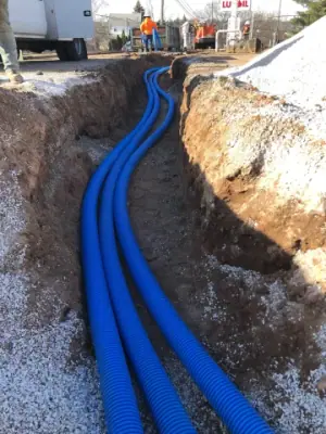 Blue piping runs laid in an open trench with aggregate bedding.