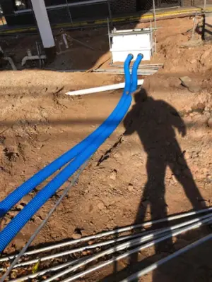 Blue piping runs cross an excavated forecourt section.
