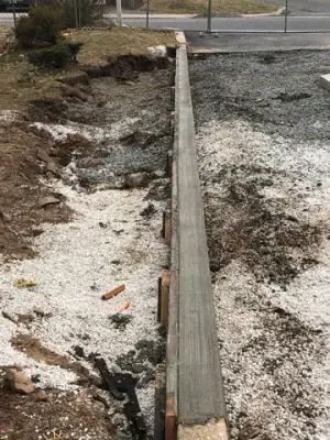 Narrow formed concrete curb beside the work area.