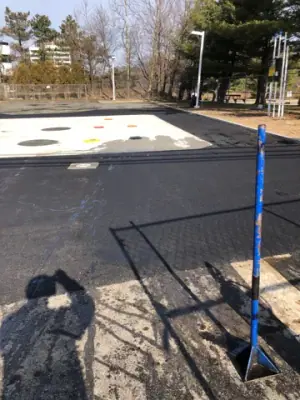 Resurfaced asphalt around the concrete tank pad.