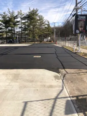 Paved forecourt between the concrete fueling area and boundary trees.