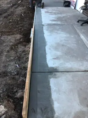 Finished walkway divided into concrete panels beside the building.