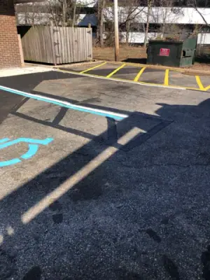 Accessible-parking symbol and yellow crosshatched area on the asphalt.